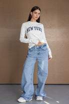 דוגמנית עם חולצת שרוול ארוך אפורה עם כיתוב NEW YORK ומכנסי ג'ינס רחבים לנשים אופנה צעירה