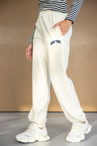 מכנסי טרנינג לבנים לנשים עם כיתוב ניו יורק, חולצת פסים ונעלי סניקרס אופנתיות