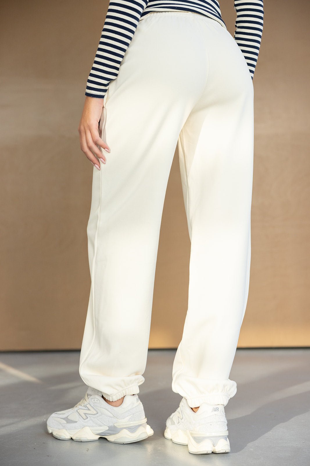 מכנסי טרנינג נשים בצבע שמנת עם נעליים לבנות, חולצה פסים, אופנת קז'ואל צעירה