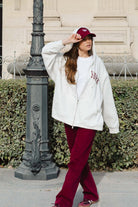 אישה עם קפוצ׳ון אפור, חולצה לבנה ומכנסיים בורדו, אופנת רחוב לנשים