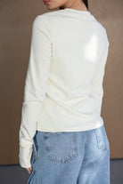 חולצת שרוול ארוך לבנה לנשים עם ג'ינס כחול בהיר, מראה קז'ואל אופנתי