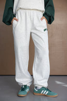 מכנסי טרנינג נשים בגזרה רחבה בצבע אפור בהיר עם כיסים, משולבים עם סווטשירט ונעלי אדידס ירוקות