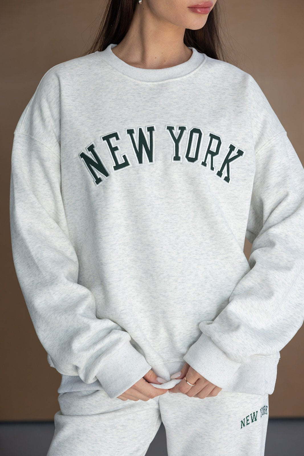 אישה לובשת סט טרנינג אפור עם כיתוב NEW YORK בחזית, אופנה לנשים צעירות