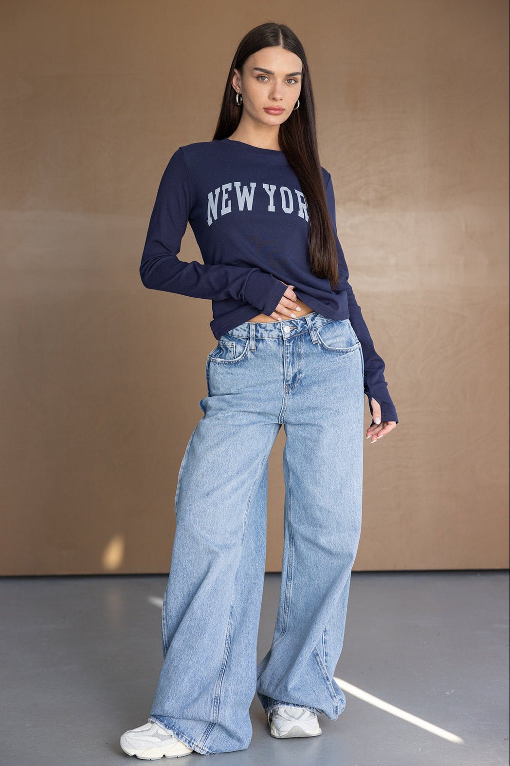 דוגמנית עם חולצת ניו יורק כחולה ומכנסי ג'ינס רחבים, אופנת נשים צעירה וטרנדית