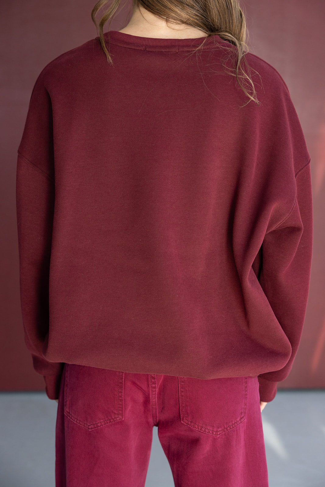 אישה לובשת סווטשירט בצבע בורדו ומכנסיים תואמים, אופנת נשים ונערות