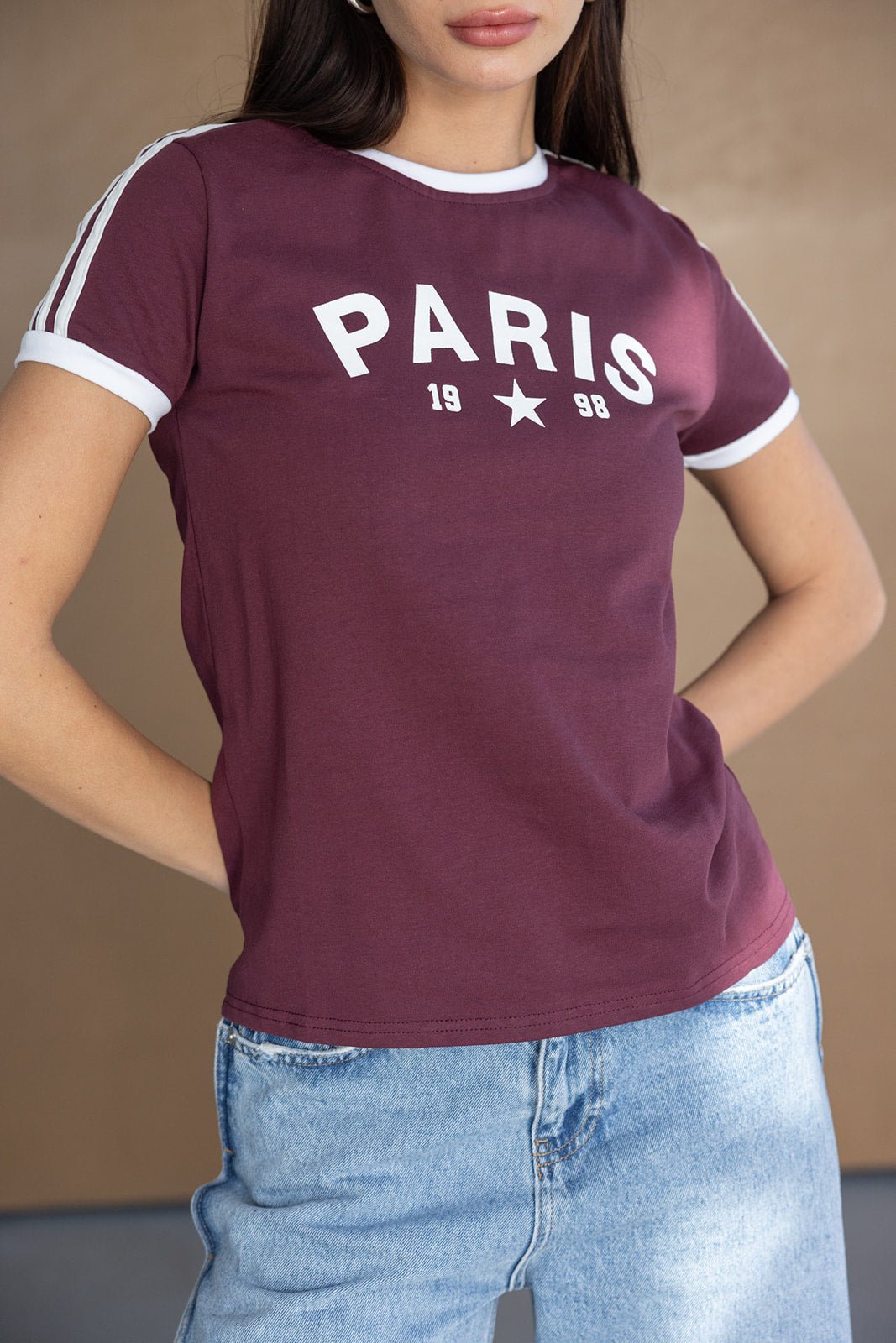 אישה לובשת חולצת טי בורדו עם כיתוב PARIS 1998 ולבוש ג'ינס, אופנה לנשים צעירות