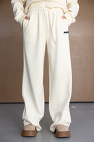 מכנסי טרנינג נשים בגזרת בוי פרנד בצבע שמנת, מותן עם גומי ושרוך, כיסים, רקמת לוגו קטנה