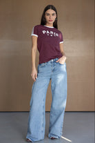 אישה עם חולצת טי בורדו עם כיתוב PARIS ומכנסי ג'ינס רחבים, אופנת נשים צעירה