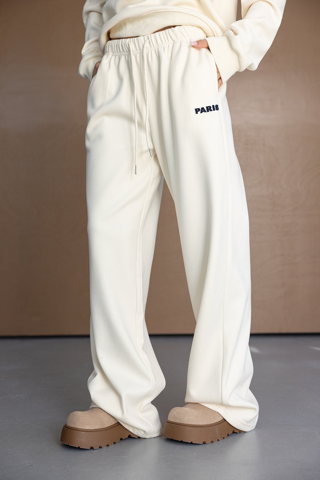 מכנסי טרנינג לנשים בצבע שמנת עם כתובת PARIS, גזרה רחבה ואופנתית, נעלי פלטפורמה בז'