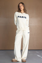 דוגמנית לובשת סט טרנינג אופנתי בצבע שמנת עם כיתוב PARIS, מתאים לאופנת נשים ונערות