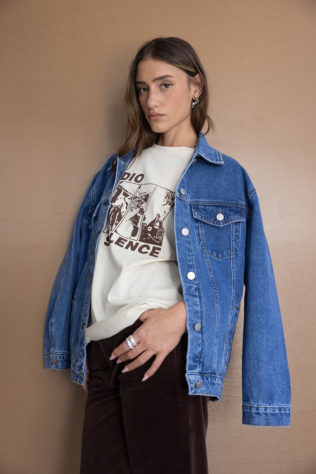 אישה צעירה עם חולצת הדפס אופנתית, ג'קט ג'ינס כחול ומכנסיים חומים, טרנד חורף לנשים