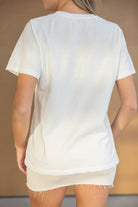 אישה לובשת חולצת טי לבנה קצרה ומכנסיים קצרים בצבע בז', מצולמת מאחור