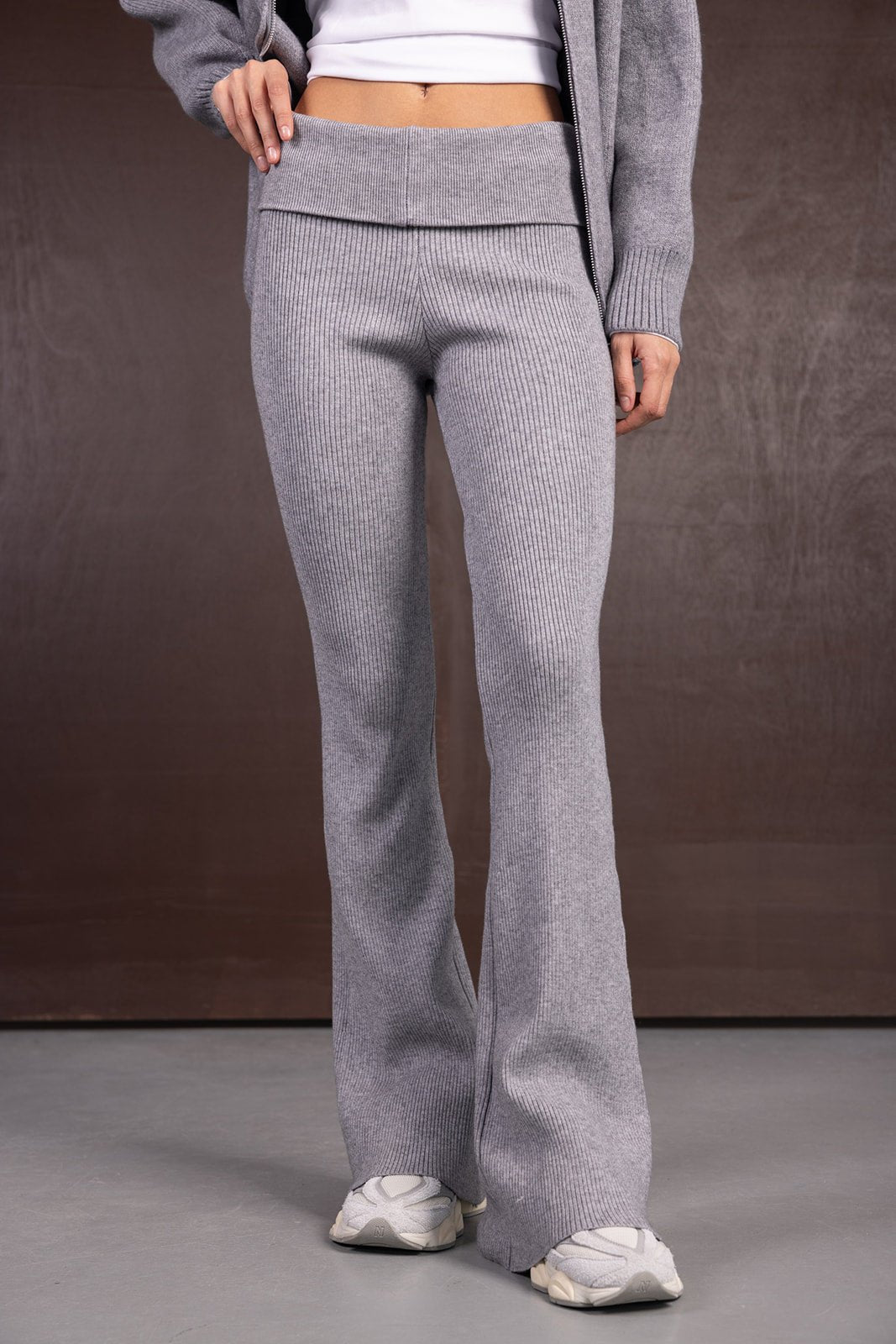 מכנסיים מחטבות לנשים בגזרת פדלפון בצבע אפור מבד סריג, עם חולצה לבנה ונעלי סניקרס