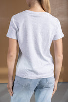 גב של אישה עם חולצת טי שירט אפורה קלאסית ומכנסי ג'ינס בגזרה גבוהה, אופנת נשים נוער