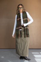 אופנת חורף לנשים: דוגמנית עם צעיף משובץ ירוק-חום, חולצה לבנה וחצאית ירוקה ארוכה