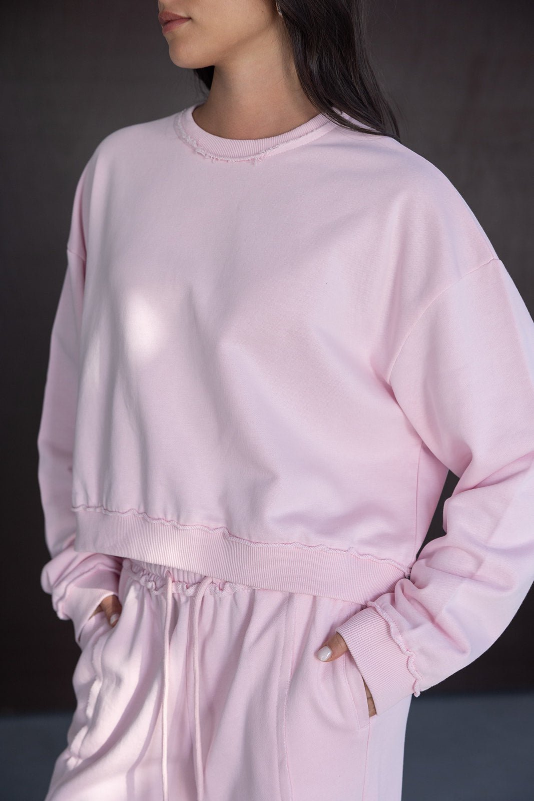 אישה לובשת סט טרנינג ורוד אופנתי לנשים, חולצה ומכנסי ספורט נוחים מבד כותנה