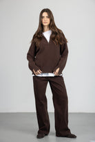 אישה לובשת סוודר חום עם רוכסן, חולצה לבנה ומכנסיים חומים, אופנה לנשים צעירות