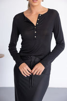 אופנת נשים, דוגמנית לובשת שמלת כפתורים ארוכה בשחור עם שרוך במותן, בד רך ואלגנטי