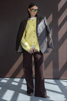 אישה עם משקפי שמש, קרדיגן צהוב פלאפי, בלייזר עור כהה ומכנסיים רחבים, לוק אופנתי לנשים