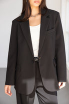 אישה לובשת בלייזר שחור קלאסי ומכנסיים מחויטים, חולצה לבנה מתחת, אופנה לנשים ונערות