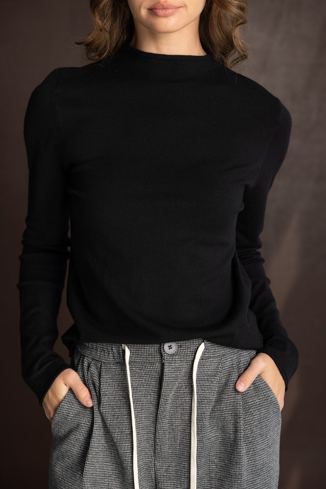 אישה לובשת סוודר שחור עם צווארון גבוה ומכנסיים מחויטים אפורים, אופנת נשים מודרנית