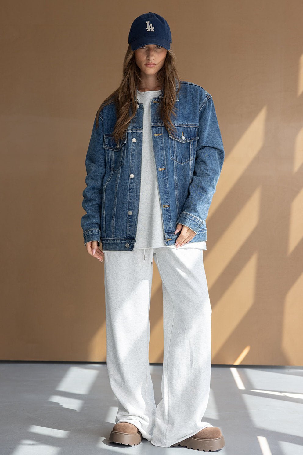 אישה לובשת ג'קט ג'ינס מעל טרנינג אפור וכובע כחול, סטייל אופנת רחוב לנשים