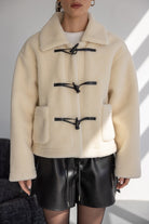 מעיל נשים פרווה בהירה עם סוגרי עור שחורים, חצאית קצרה דמוי עור, מראה אופנתי חורפי