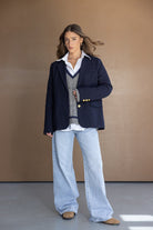 אישה עם בלייזר כחול, סוודר אפור, חולצה לבנה ומכנסי ג׳ינס רחבים, לוק אלגנטי קז'ואל