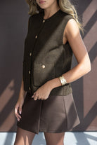 דוגמנית לובשת אפודה סרוגה חומה ללא שרוולים עם כפתורים וחצאית חומה, אופנה לנשים צעירות