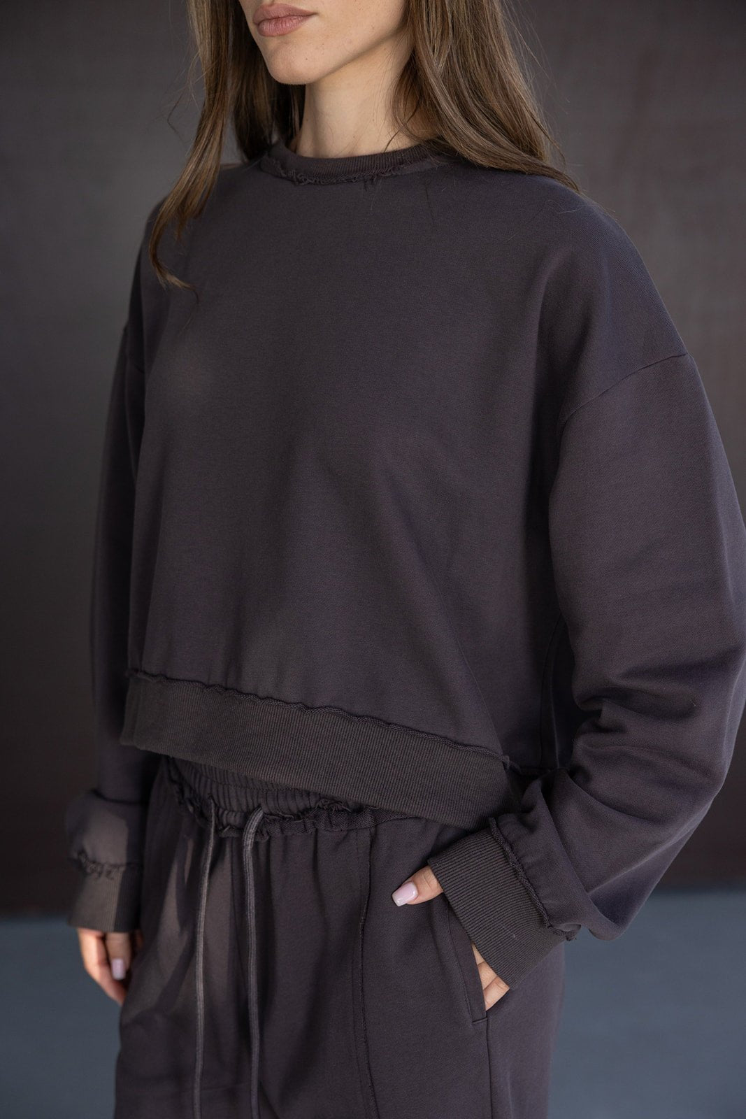 אישה עם סט טרנינג אופנתי בצבע כהה, חולצת סווטשירט ומכנסיים עם גומי ומתאימים לאופנת נשים צעירות