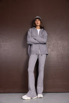 דוגמנית לובשת סט ספורט אפור עם קפוצ׳ון מכנסיים רחבים, כובע מצחייה ונעלי סניקרס אופנתיות