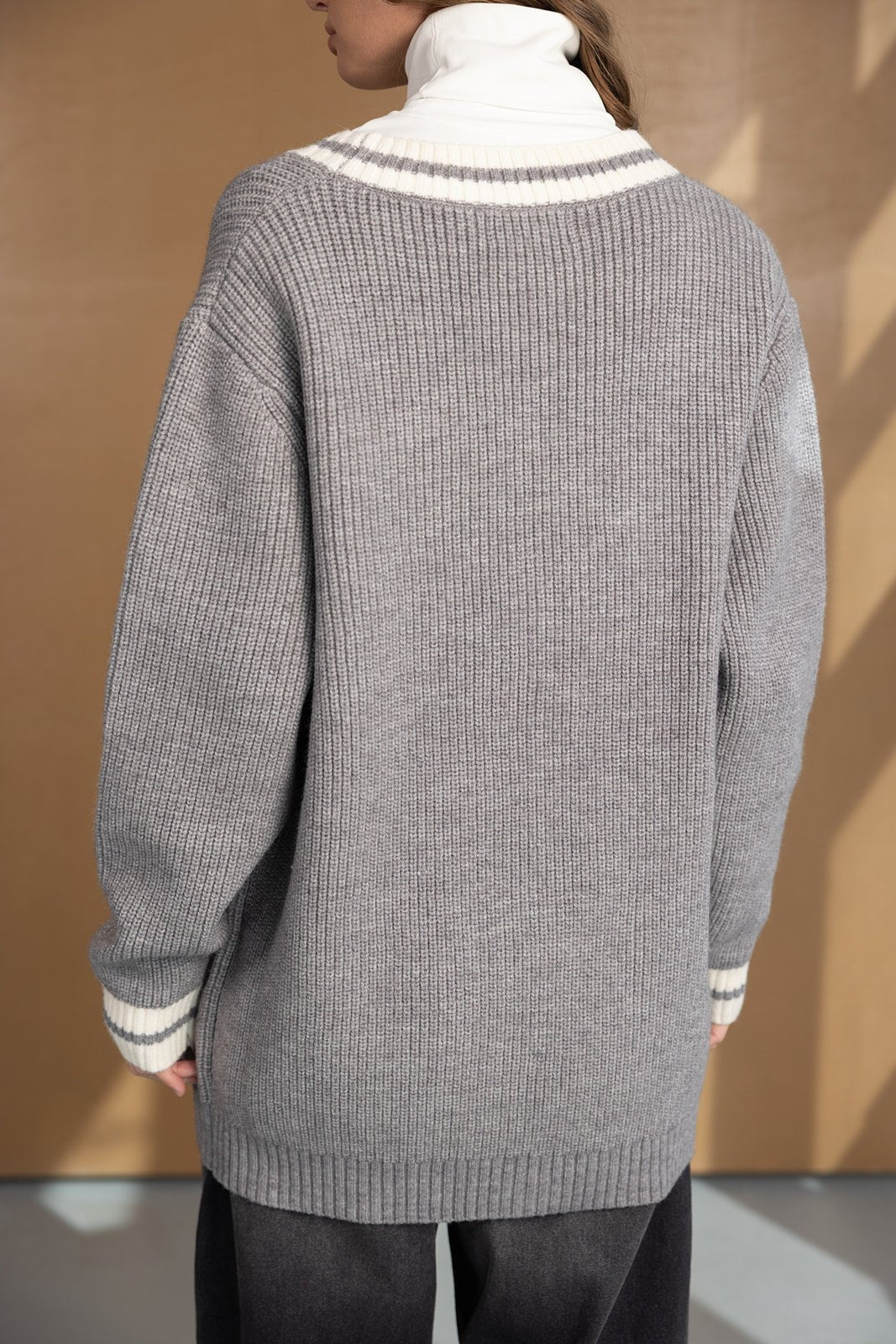 אישה עם סוודר סרוג בצבע אפור עם צווארון גבוה לבן, בסגנון חורפי אופנתי