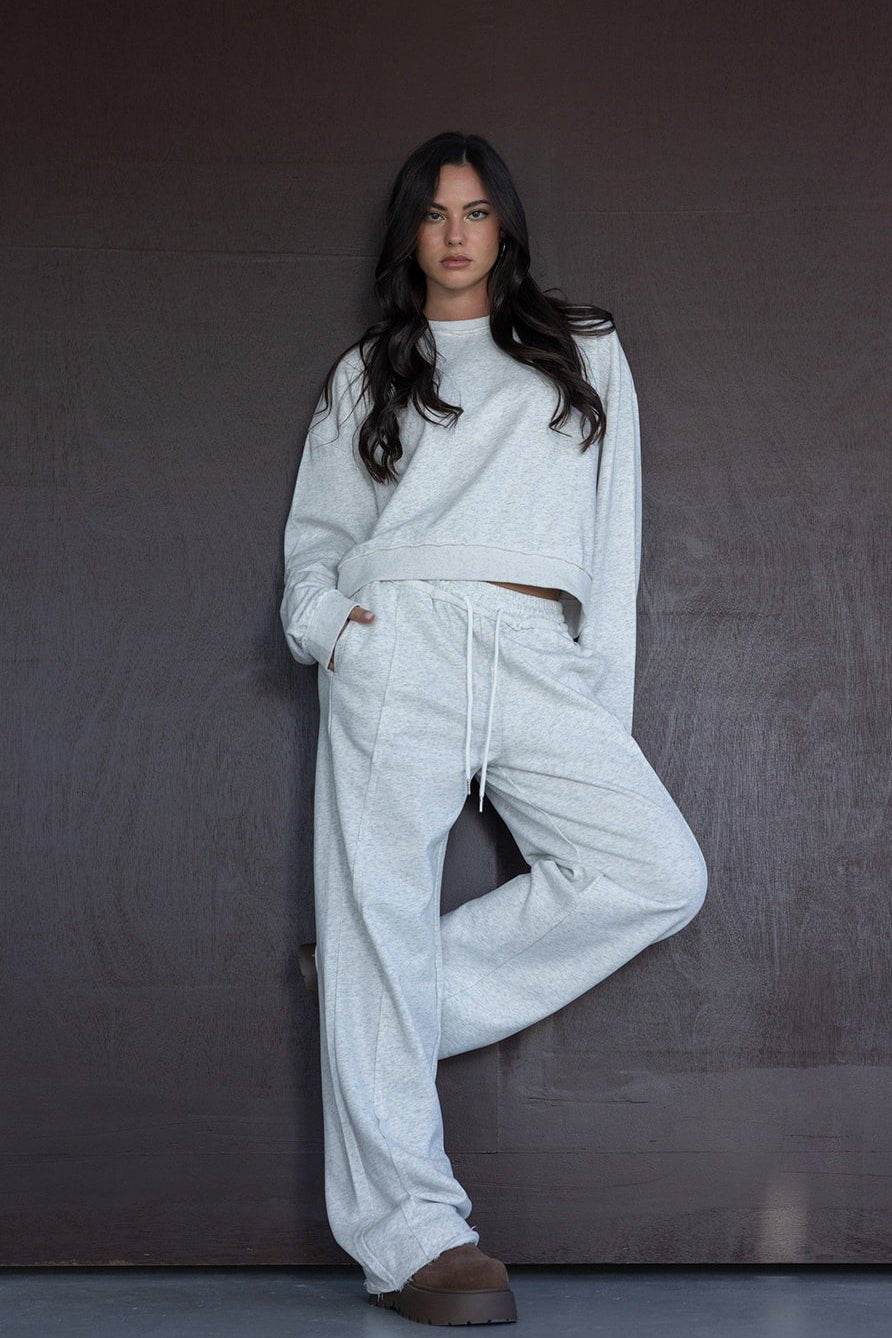 אישה לובשת סט טרנינג אפור אופנתי עם מכנסיים רחבים וסווצ'ר, נעלי חורף חומות, אופנת נשים צעירה