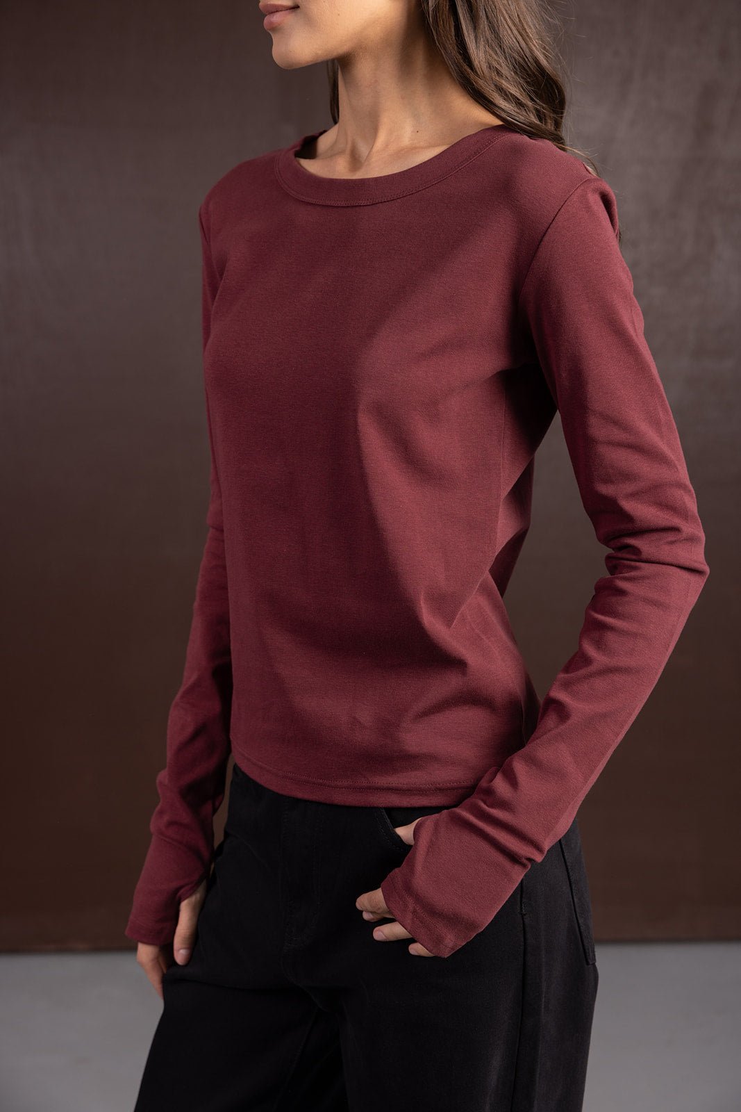 חולצת נשים ארוכה בורדו עם שרוולים ארוכים, אופנת חורף לנשים, צולם על רקע חום