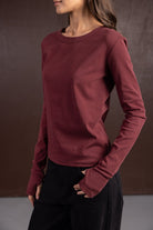 חולצת נשים ארוכה בורדו עם שרוולים ארוכים, אופנת חורף לנשים, צולם על רקע חום