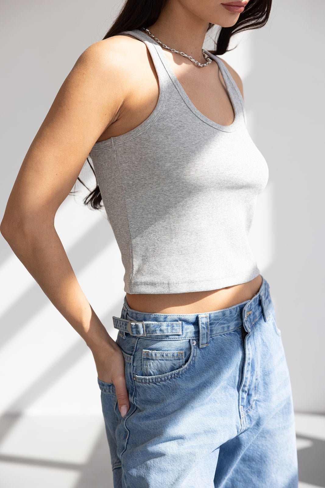 אישה עם גופיית סבא אפורה ומכנסי ג'ינס בגזרה גבוהה, אופנה לנשים צעירות