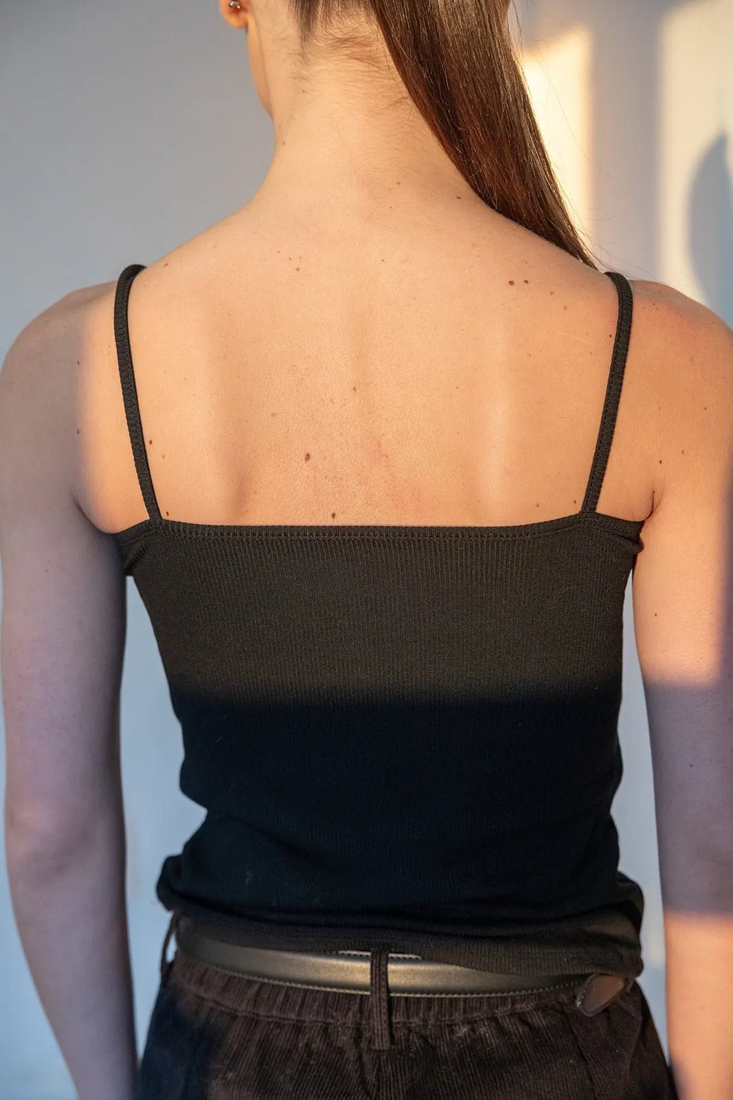 גופיית נשים שחורה עם כתפיות דקות, צילום מאחור, אופנת קיץ לנשים ונערות