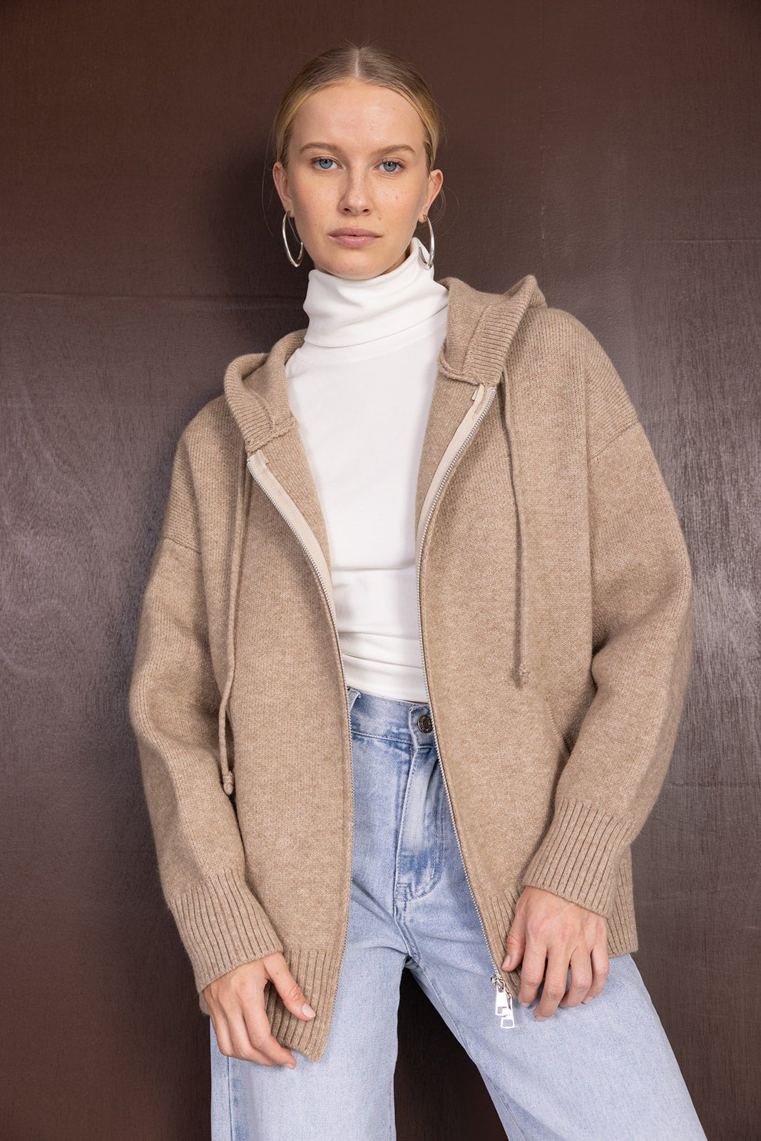 דוגמנית עם סוודר קפוצ'ון בז', גולף לבן ומכנסי ג'ינס אופנתיים לצעירות