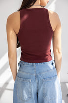 אישה עם גופיית בורדו צמודה וג'ינס רחב בגזרת אמא, אופנת נשים מודרנית