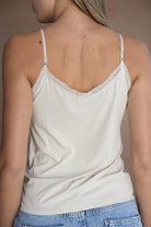 גופיית נשים קיצית בצבע שמנת עם תחרה עדינה בכתפיות דקות, בשילוב ג'ינס בהיר