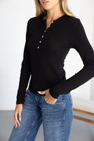 חולצת נשים שחורה עם שרוול ארוך וכפתורים, משולבת עם ג'ינס קז'ואל אופנתי