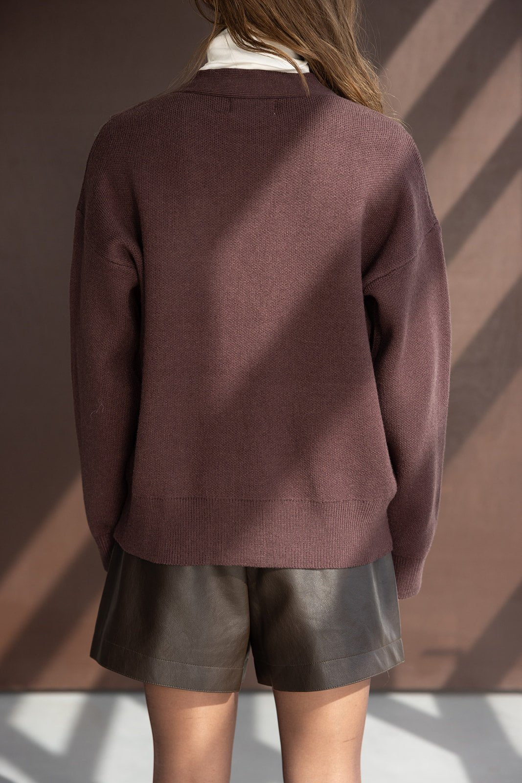 דוגמנית לובשת סוודר בורדו קצר ומכנסי עור שחורים לנערות, צילום אופנה גב