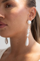 עגילי פנינה תלויים לנשים, עיצוב אלגנטי בגוון לבן וזהב, צילום תקריב על דוגמנית