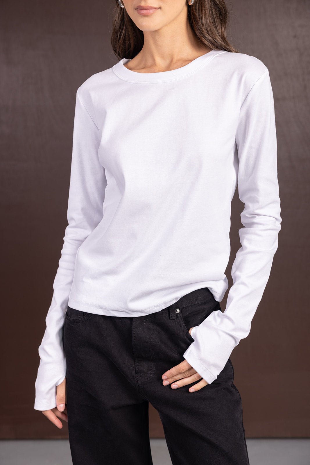 דוגמנית לובשת חולצת בייסיק לבנה עם שרוולים ארוכים ומכנסיים שחורים, אופנת נשים צעירה