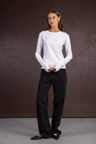 אישה לובשת חולצת בסיס לבנה עם שרוולים ארוכים ומכנסיים שחורים רחבים, אופנת קז'ואל לנשים