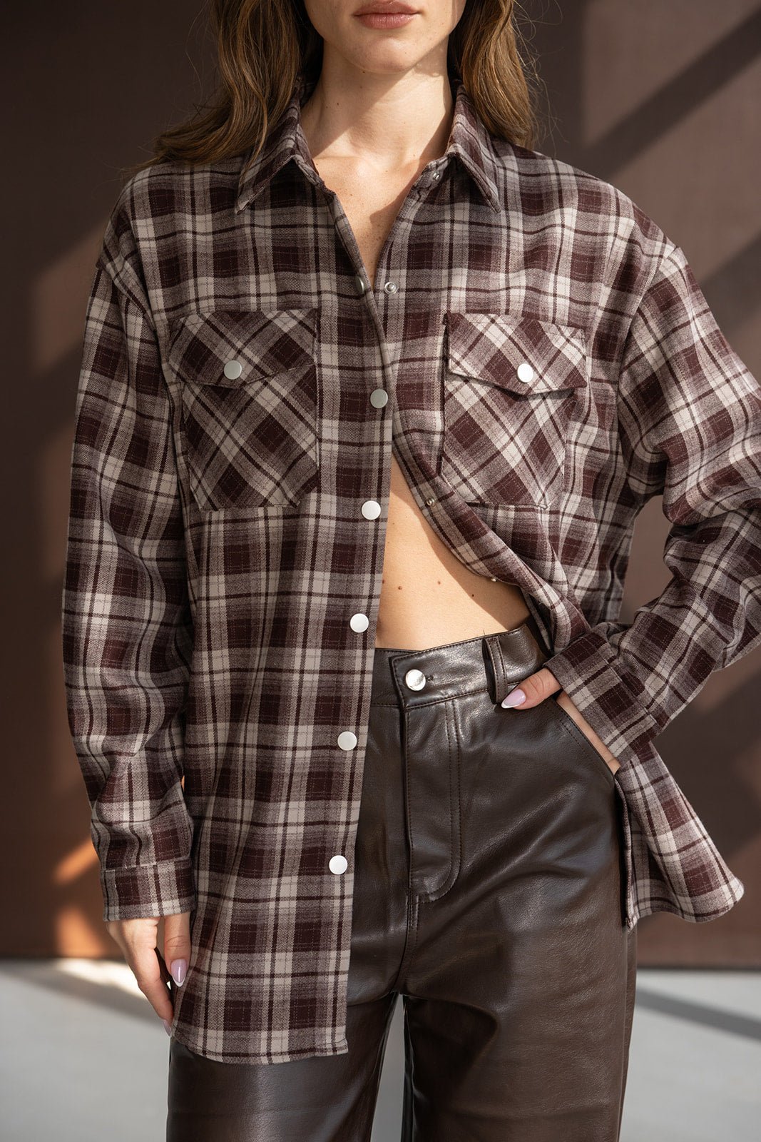 חולצת פלנל משובצת חום ובז' לנשים עם כיסים קדמיים, משולבת עם מכנסי עור חום אופנתיים