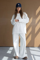 אישה צעירה לובשת סט טרנינג אפור קז'ואל וכובע כחול, אופנת נשים מודרנית ויומיומית