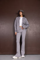 אישה לובשת סט סריג אפור עם קפוצ'ון, טי שירט לבנה וכובע מצחייה, אופנה יומיומית לנשים