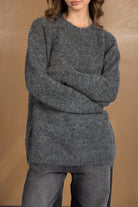 דוגמנית לובשת סוודר אפור לנשים עם מרקם רך ומכנסיים בגוון כהה, אופנת חורף קז'ואל