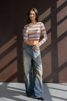 אישה לובשת ג'ינס רחב וטופ פסים ורוד-חום ארוך שרוול, אופנה לנשים צעירות